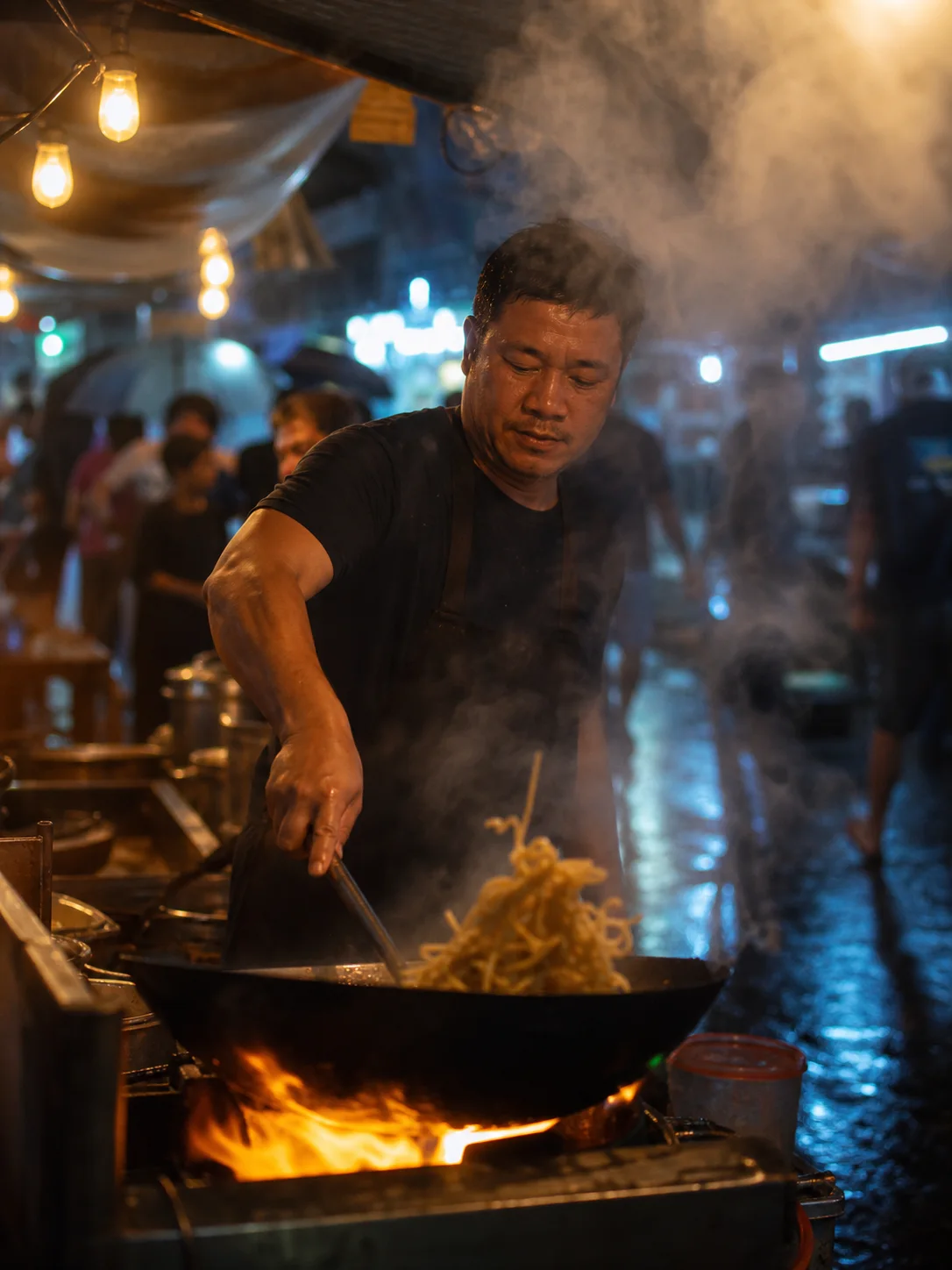 Street-food chef tossing noodles in a steaming wok